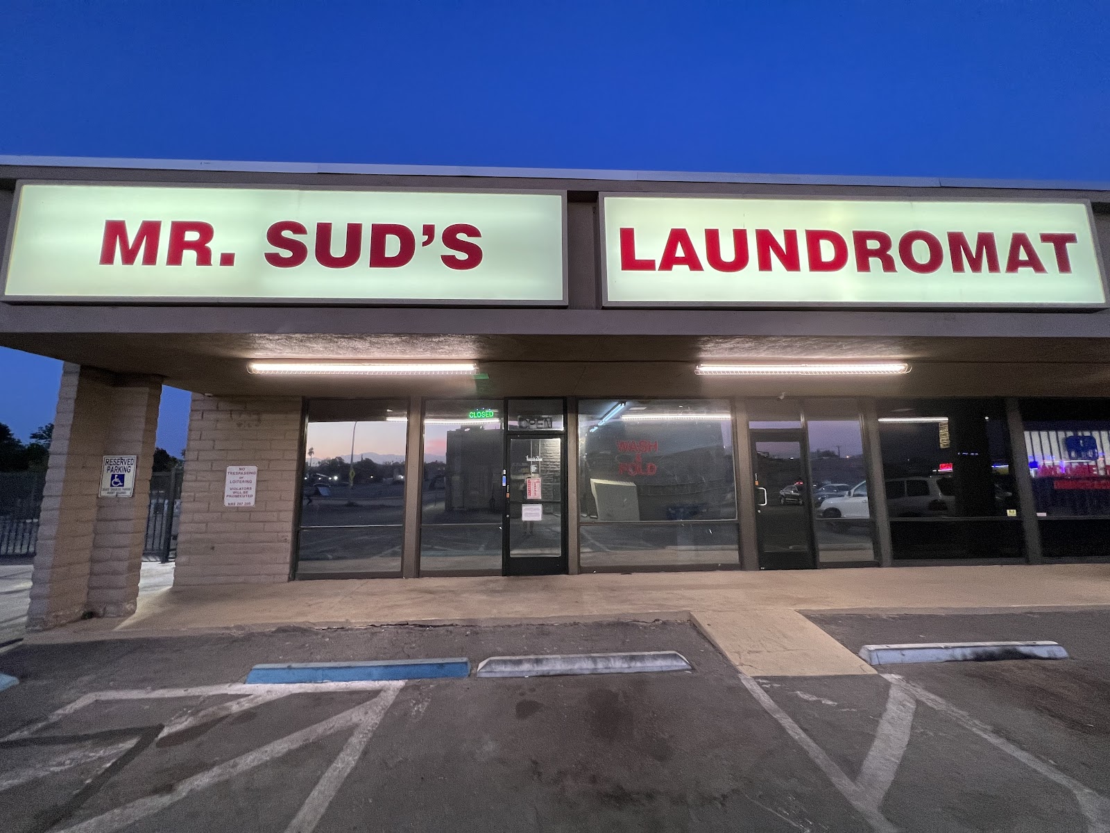Illuminated Mr. Sud's Laundromat storefront sign at dusk